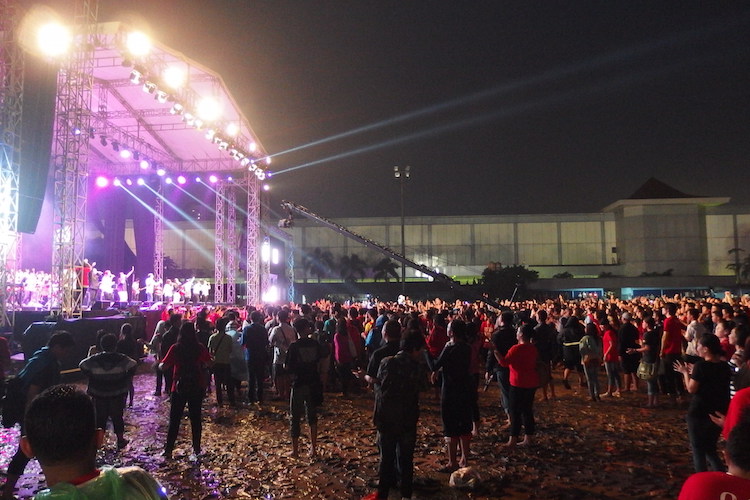 Audience members clap joyously despite the mud and rain - CY Hoon Audience members clap joyously despite the mud and rain - CY Hoon